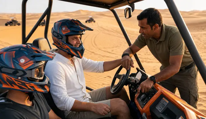 Instructor in khaki polo guiding a smiling man in a white shirt and helmet inside an orange dune buggy in the Abu Dhabi Desert, with other buggies visible on the dunes.