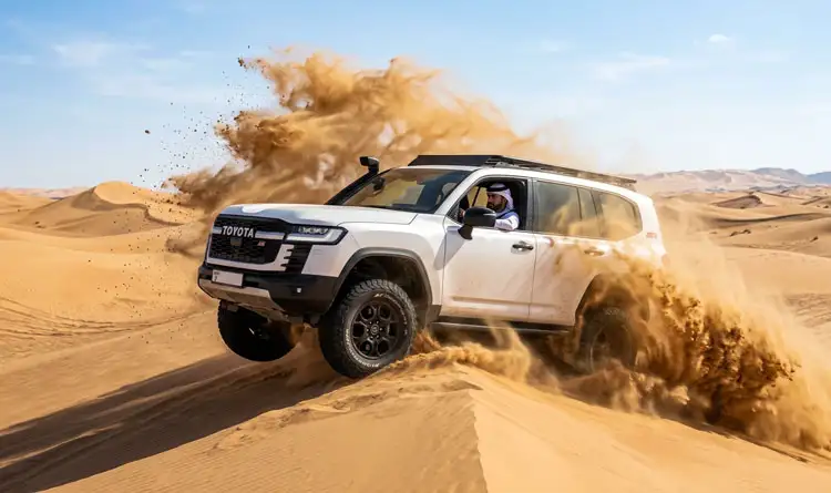 A 4x4 Land Cruiser surging through the sand dunes in Abu Dhabi during an exciting overnight desert safari adventure.