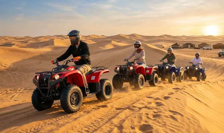 A guided group on quad bike tours Abu Dhabi riding ATVs in a line across the golden desert sand dunes during a sunset safari adventure.